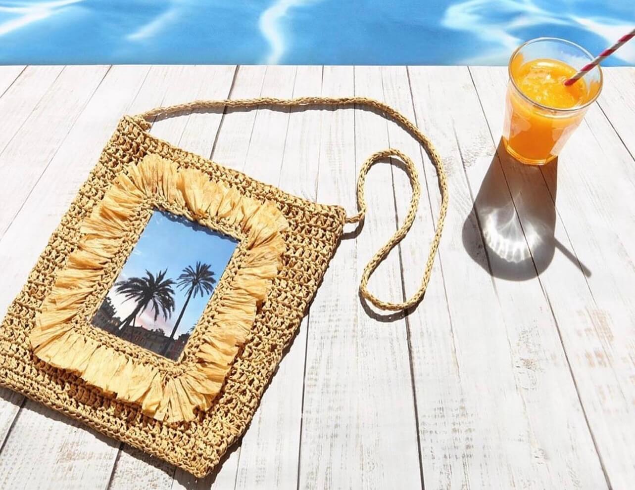un sac de plage crocheter en raphia naturel au bord de l'eau avec un cocktail